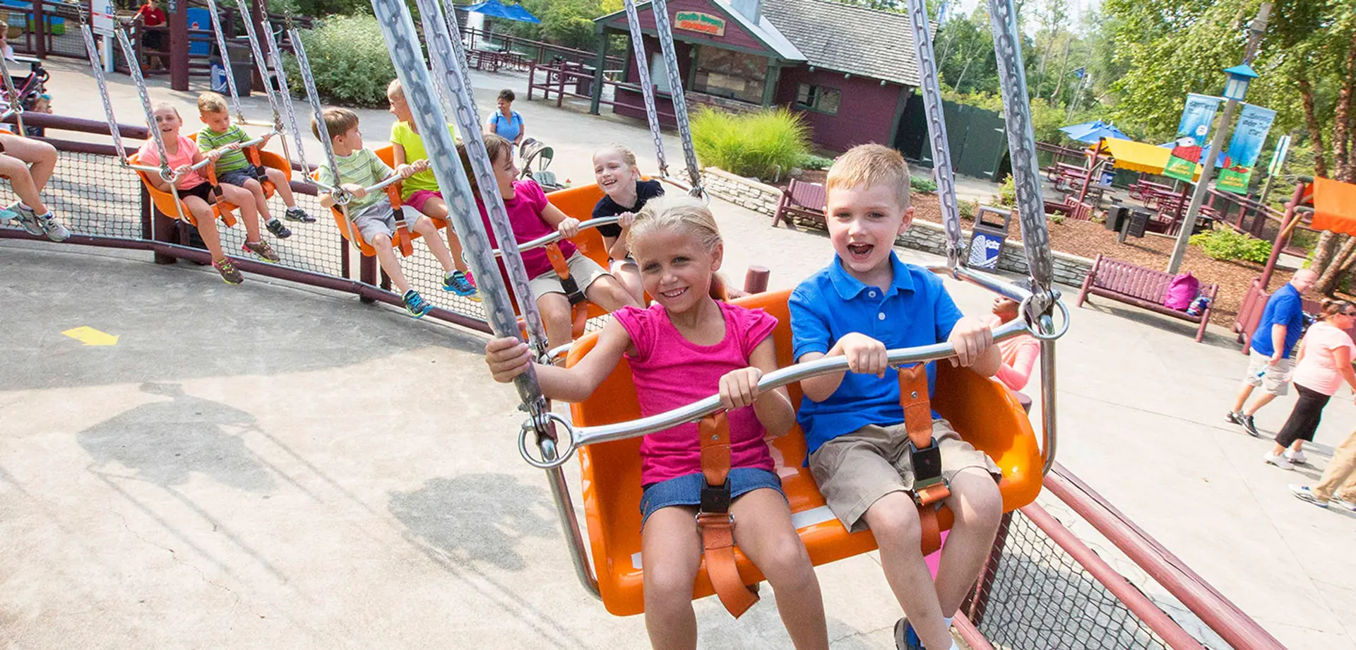 Smiling children enjoy a circular swing ride.